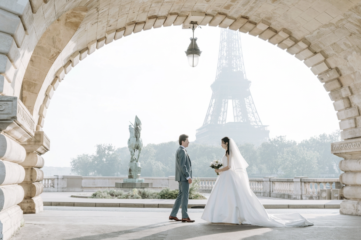 Pareja de novios bajo un arco de piedra con la Torre Eiffel al fondo